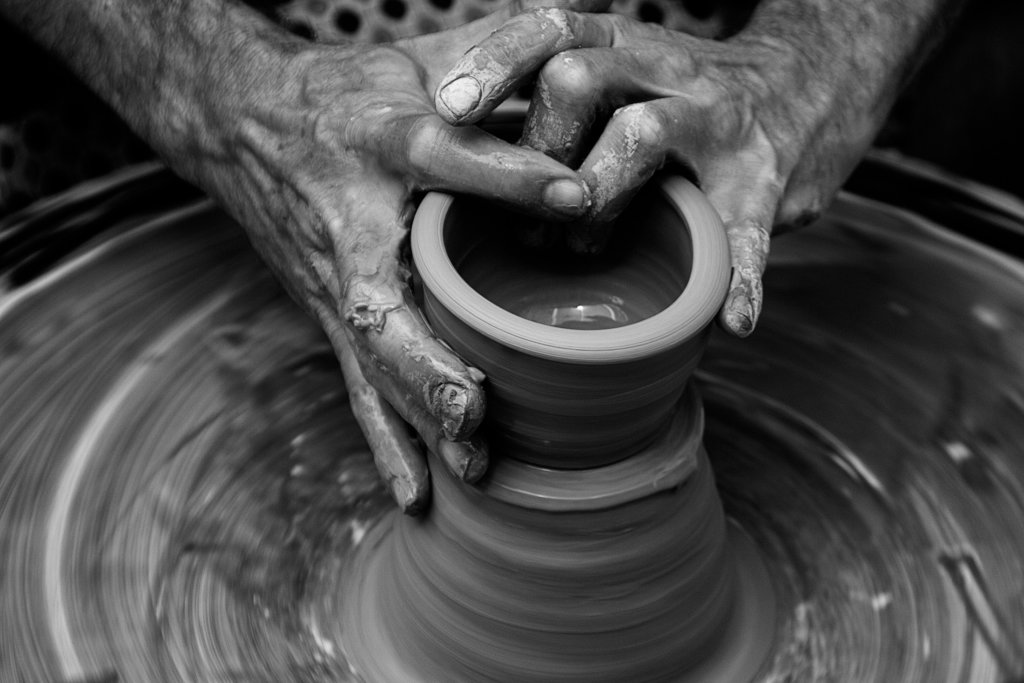 person throwing ceramic bowl on a pottery wheel